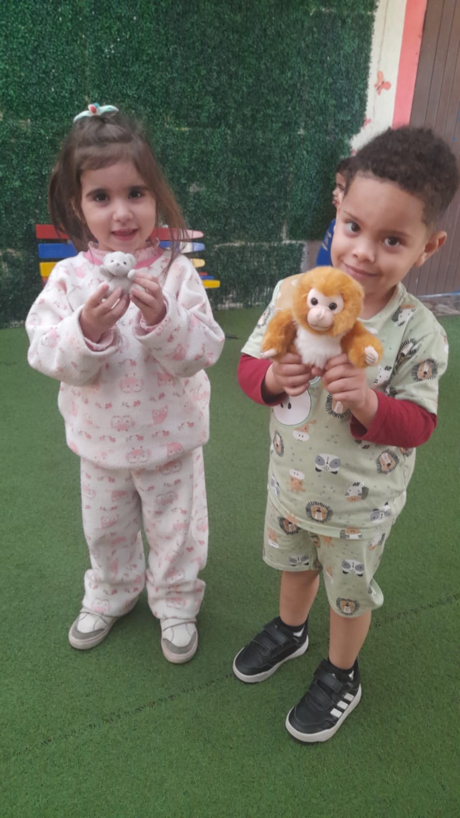 Duas crianças de pijama segurando pelúcias no dia do pijama