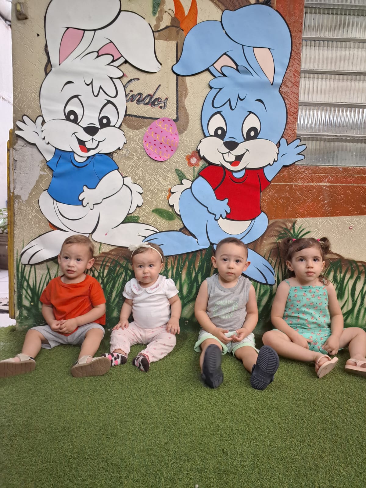 Bebês do berçário sentados no gramado da escola