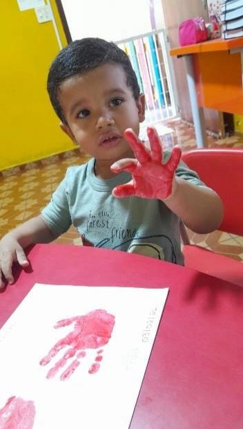 Criança pintando com as mãos durante a aula de artes