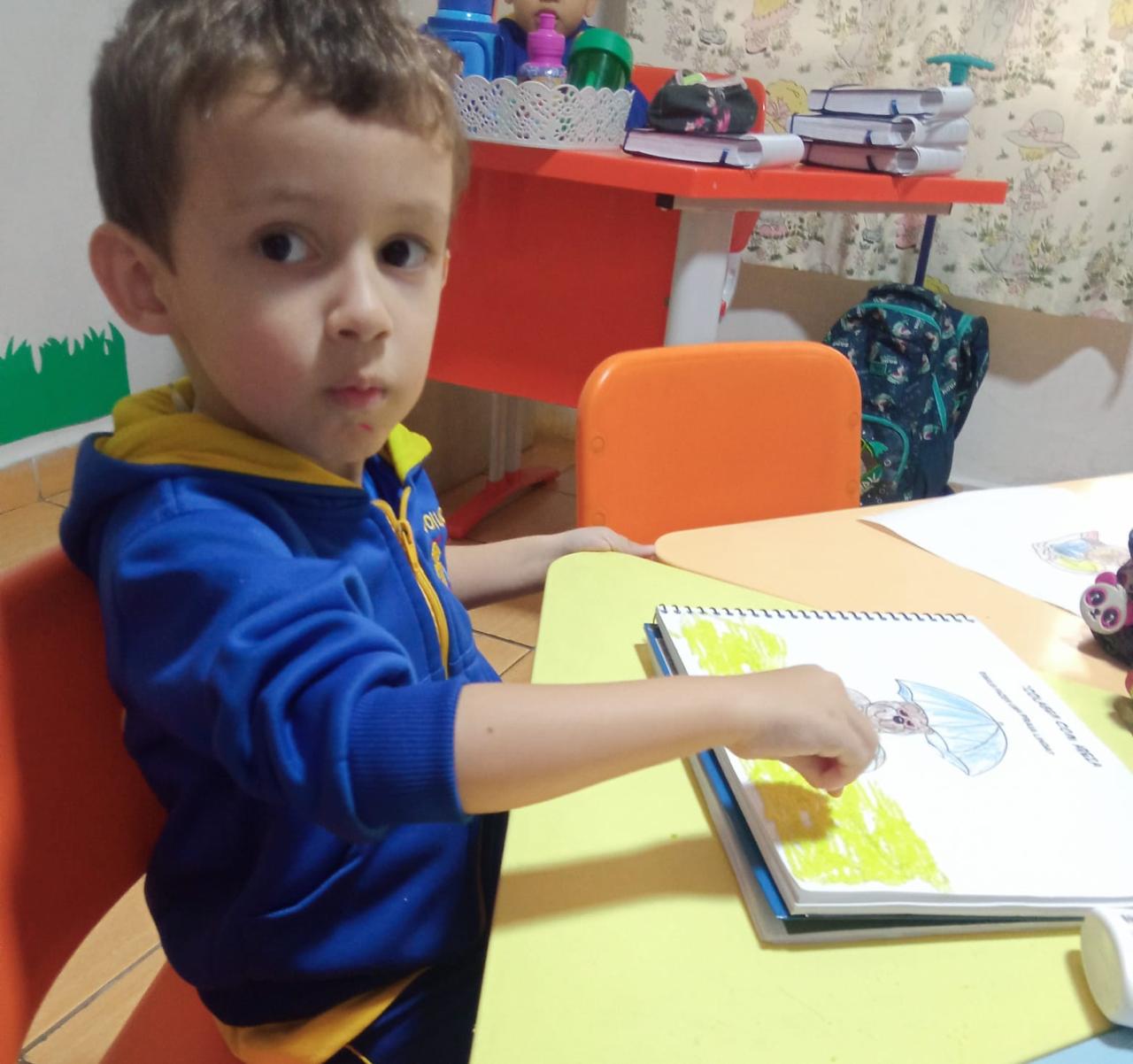 Criança colorindo desenho com giz de cera na aula de artes