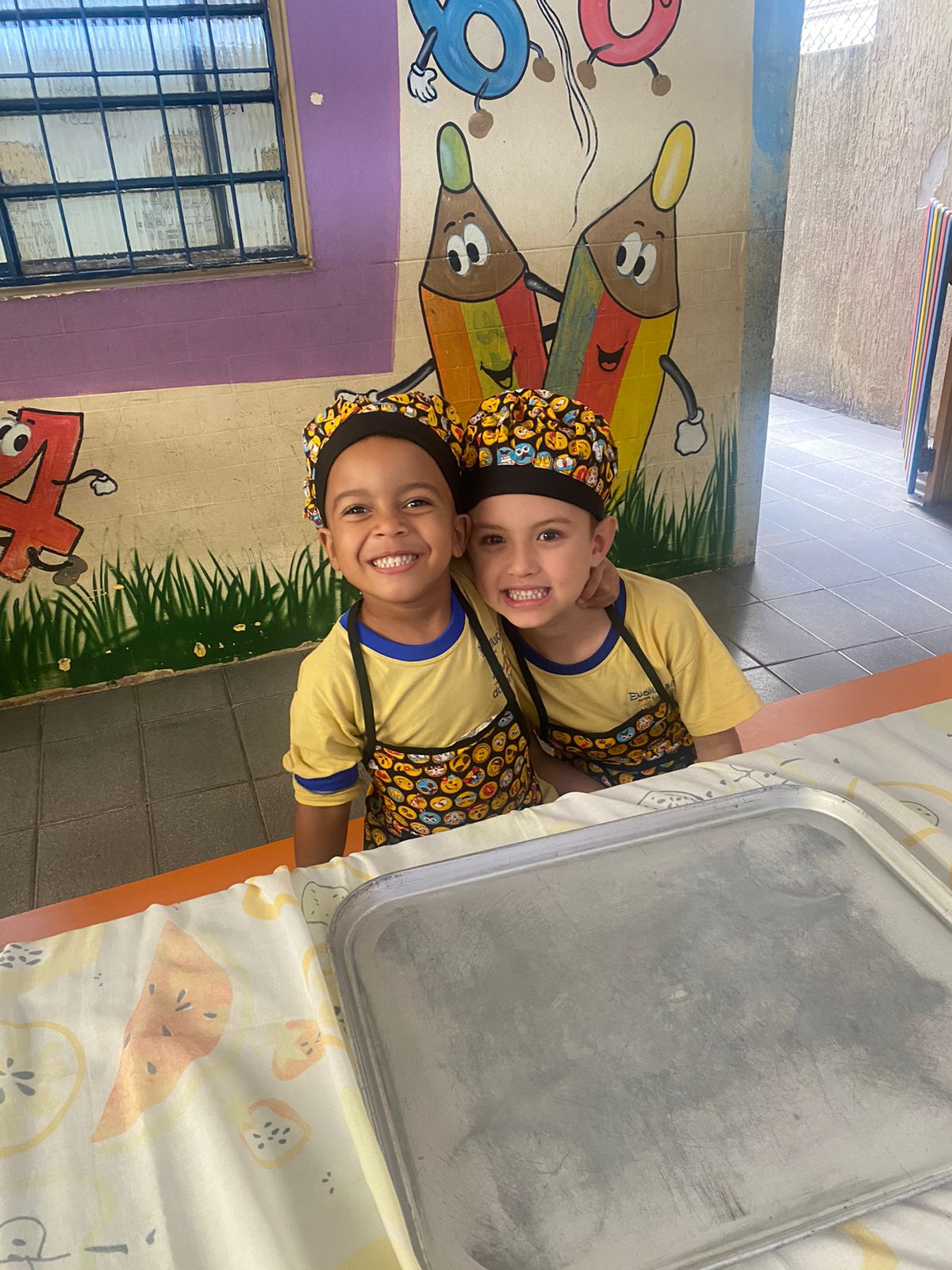 Duas crianças de touca e avental na aula de culinária