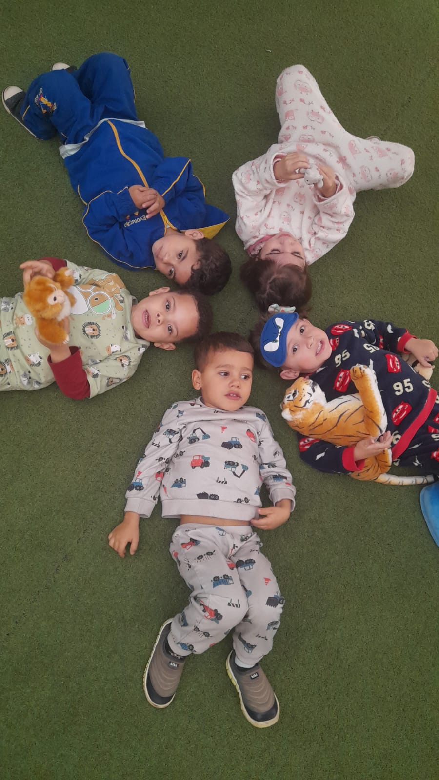 Crianças de pijama deitadas em roda no dia do pijama
